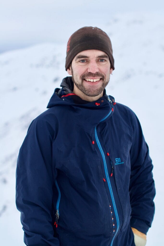 Portrett av guide og medier i Wild Voss Øystein Ormåsen med et hvitt vinterlandskap i bagrunnen.